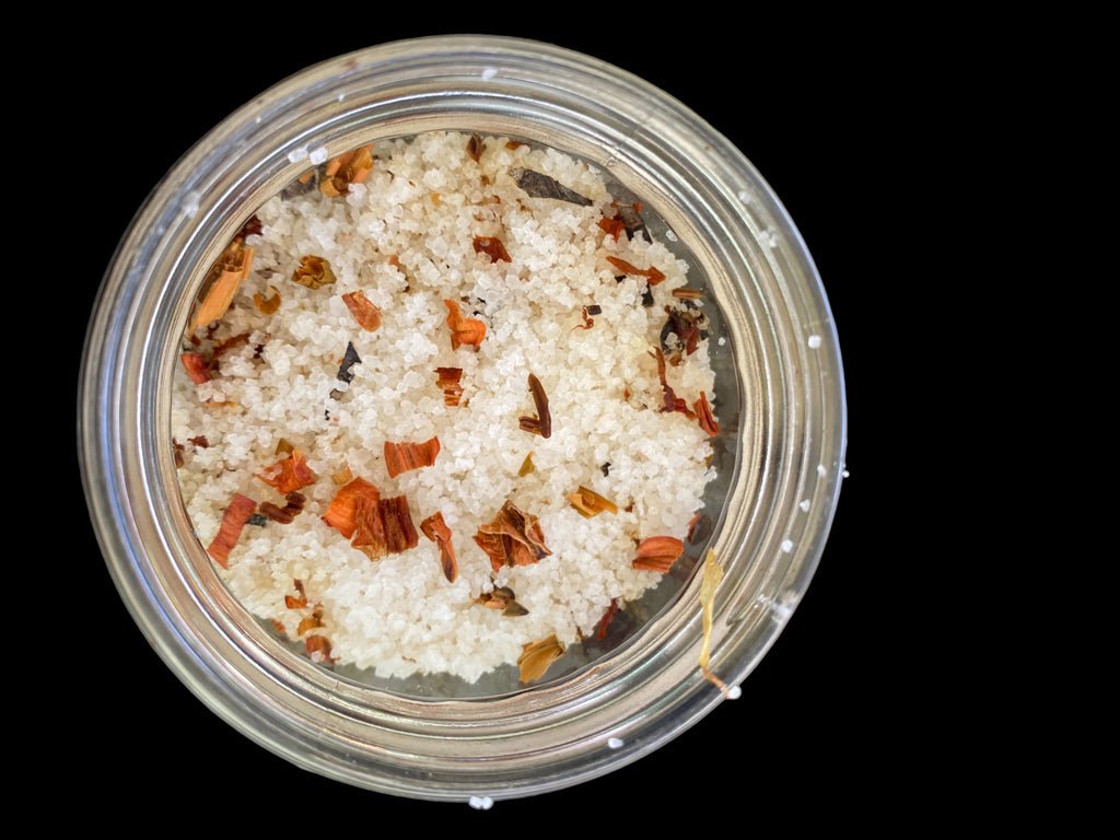 Clear Vintage Mason Jar Filled with Clove Lavender/Chamomile Tea Tree and Geranium Essential Oils has Dead Sea Salt Pink Himalayan Sea Salt has Olive Jojoba Sunflower and Shae Butter Oils. Has Lily Flowers with Calendula Flowers.