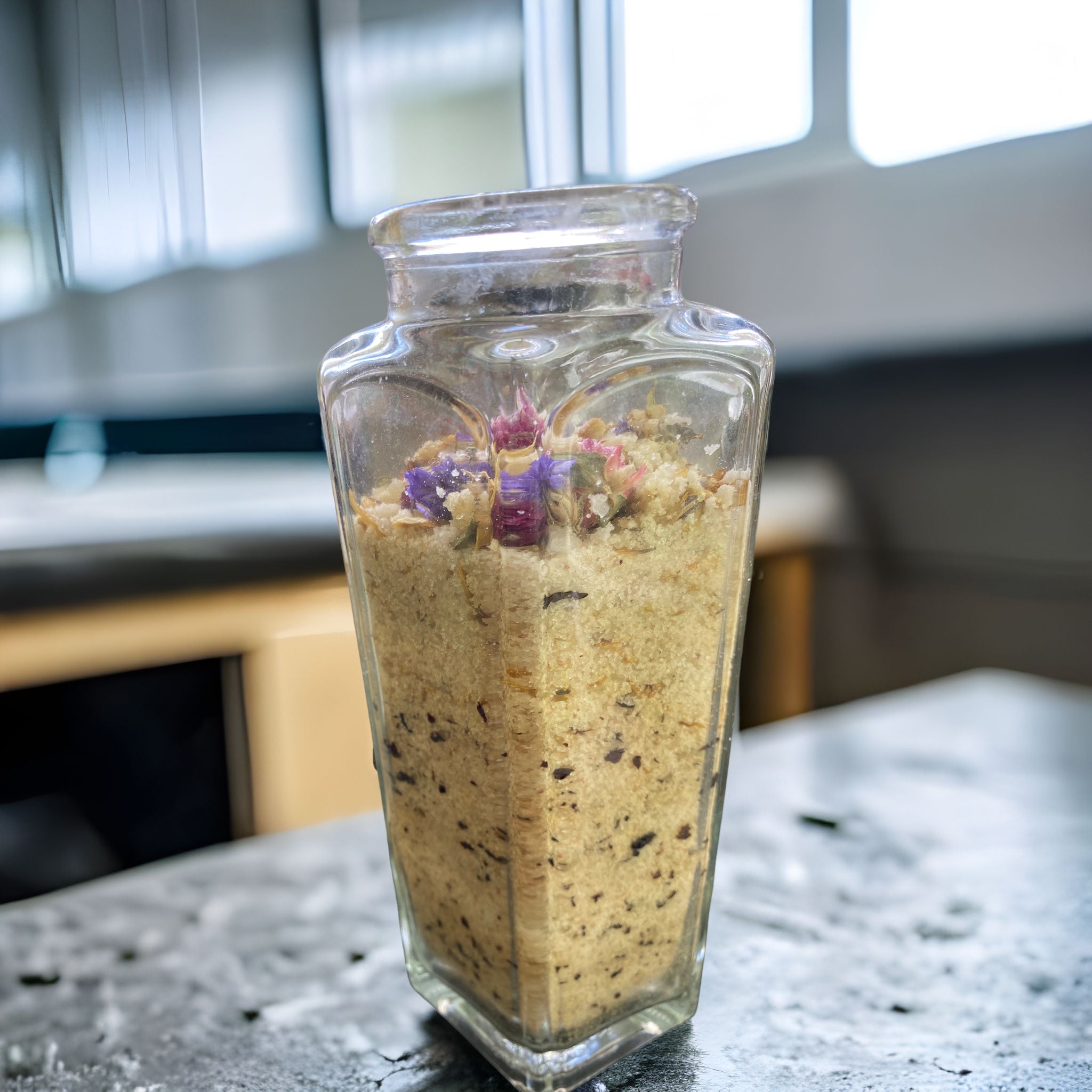 Large Clear Wedge Jar with Essence of Jojoba and Olive Oil Pure Ancient Himalayan Sea Salt with Flowers of Lavender Calendula Rose Petals has Essential Oils Tea Tree Lavender and Chamomile Topped with Don't Forget Me Flowers and Purple Gomphrena.